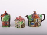 trois théières en céramique ornées de maisons, disposées les unes à côté des autres
