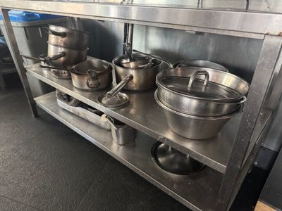 de nombreuses casseroles et poêles posées sur une étagère en métal dans la cuisine