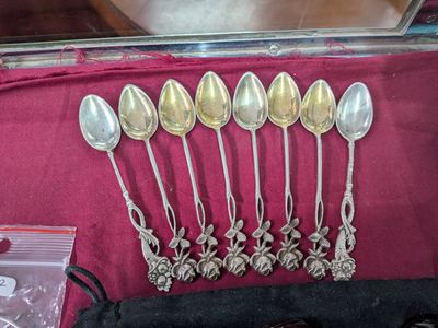 six cuillères en argent sont alignées sur une nappe rouge