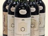 six bottles of wine are lined up in a row on a white surface