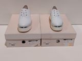une paire de chaussures blanches posée sur une boîte, elle-même posée sur une surface blanche