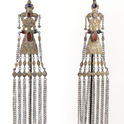two pairs of earrings with chains hanging from them on a white surface