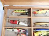 many different types of fishing lures in a wooden box
