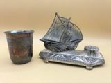 une coupe en argent posée à côté d'un bateau en argent sur une table