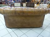 a brown leather couch sitting on a tile floor in a room
