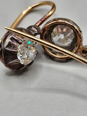 une photo en gros plan d'une paire de boucles d'oreilles posées sur une surface blanche