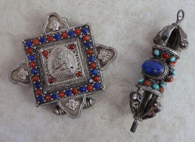 deux bijoux argentés, rouges et bleus posés sur un fond blanc