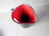 a red vase that is sitting on a white table