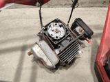 a small engine sitting on the ground next to a red car