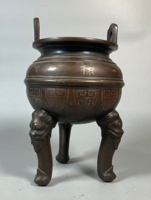 a large bronze pot on a stand with two legs