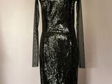 robe noire à paillettes posée sur un mannequin devant un mur rose
