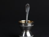 a silver spoon in a silver bowl on a black background