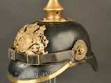 an old helmet with a gold decoration on it on a stand