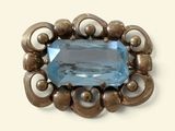 une photo d'une broche sertie d'une topaze bleue