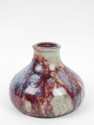 un petit vase posé sur une surface blanche