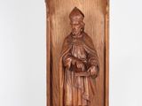 carved wooden statue of a man holding a book in his hands