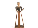 une petite statue représentant une femme debout sur un socle en bois