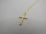 un collier avec une croix en or sur un fond gris