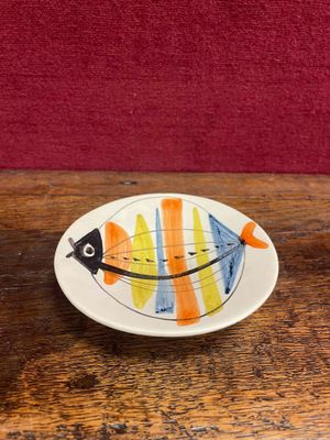 une petite assiette posée sur une table, sur laquelle se trouve un poisson
