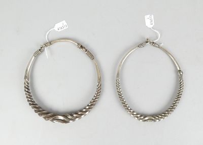 paire de boucles d'oreilles créoles en argent aux extrémités torsadées, sur fond blanc