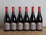 six bottles of red wine lined up on a wooden table