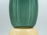 a green vase sitting on top of a yellow base