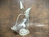 a glass vase with a bird on it on a table