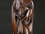 une statue en bois représentant un homme tenant un livre entre ses mains