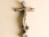une croix en bois accrochée au mur à côté d'un morceau de bois