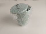 a green vase with a lid wrapped in plastic