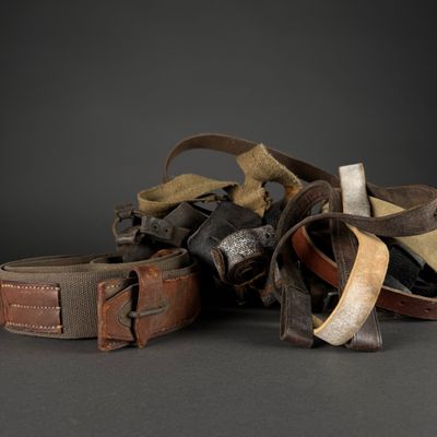 a pile of old leather belts on a black background