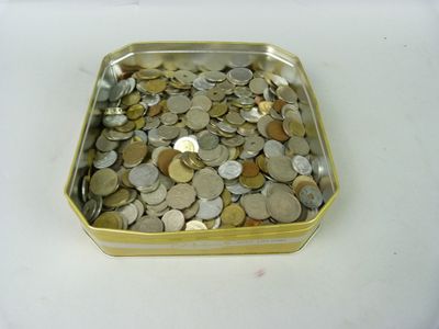 un récipient métallique rempli de pièces de monnaie posé sur une surface blanche