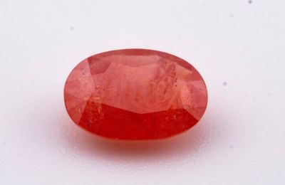 un gros plan d'une pierre ovale rouge posée sur une surface blanche