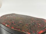 a small wooden box with a red and black design on it