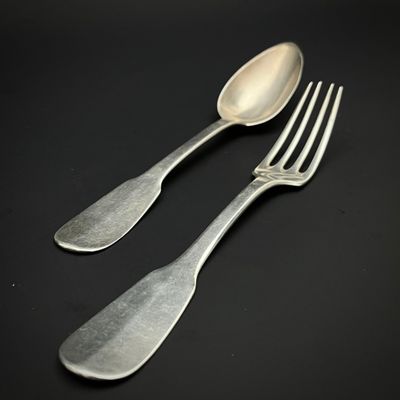 deux cuillères et une fourchette en argent sur une surface noire