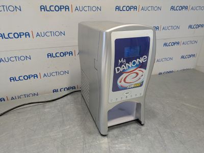 a soda dispenser sitting on the floor in front of a wall