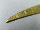 a gold plated knife with a handle on a white surface