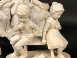 two figurines of a woman and two children on a bench