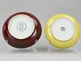 pair of yellow and red porcelain plates on stands on a gray surface