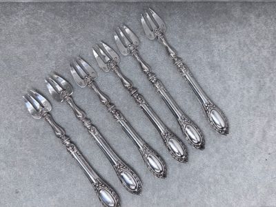 six fourchettes et cuillères en argent plaqué, posées sur un fond gris