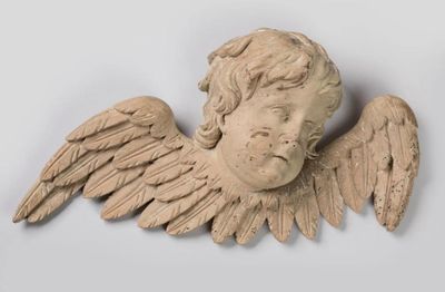 une statue représentant un ange ailé posée sur un socle blanc