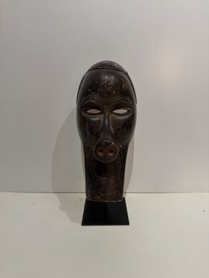 an image of a wooden mask sitting on top of a white table