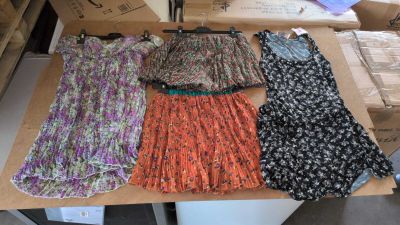 quatre robes posées sur une table, avec des piles de cartons en arrière-plan
