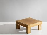 une table basse en bois posée sur une surface blanche, avec un mur gris en arrière-plan
