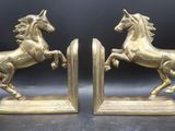 une paire de serre-livres en laiton représentant des chevaux, sur fond noir