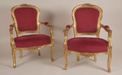 paire de chaises dorées avec des coussins rembourrés rouges et des bordures dorées