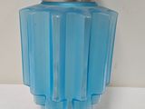 vase en verre bleu avec un couvercle argenté, posé sur une surface blanche