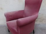 a pink chair sitting against a white wall