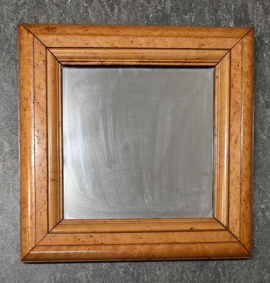 un gros plan d'un miroir accroché au mur, avec un cadre en bois
