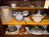 many plates and pans on a shelf in a cabinet